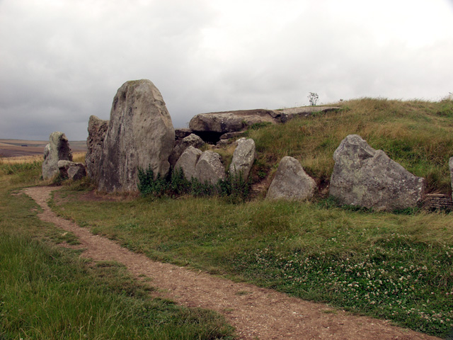 A photo showing a mound of earth overgrown with grass. The mound is reinforced with a number of large stones.